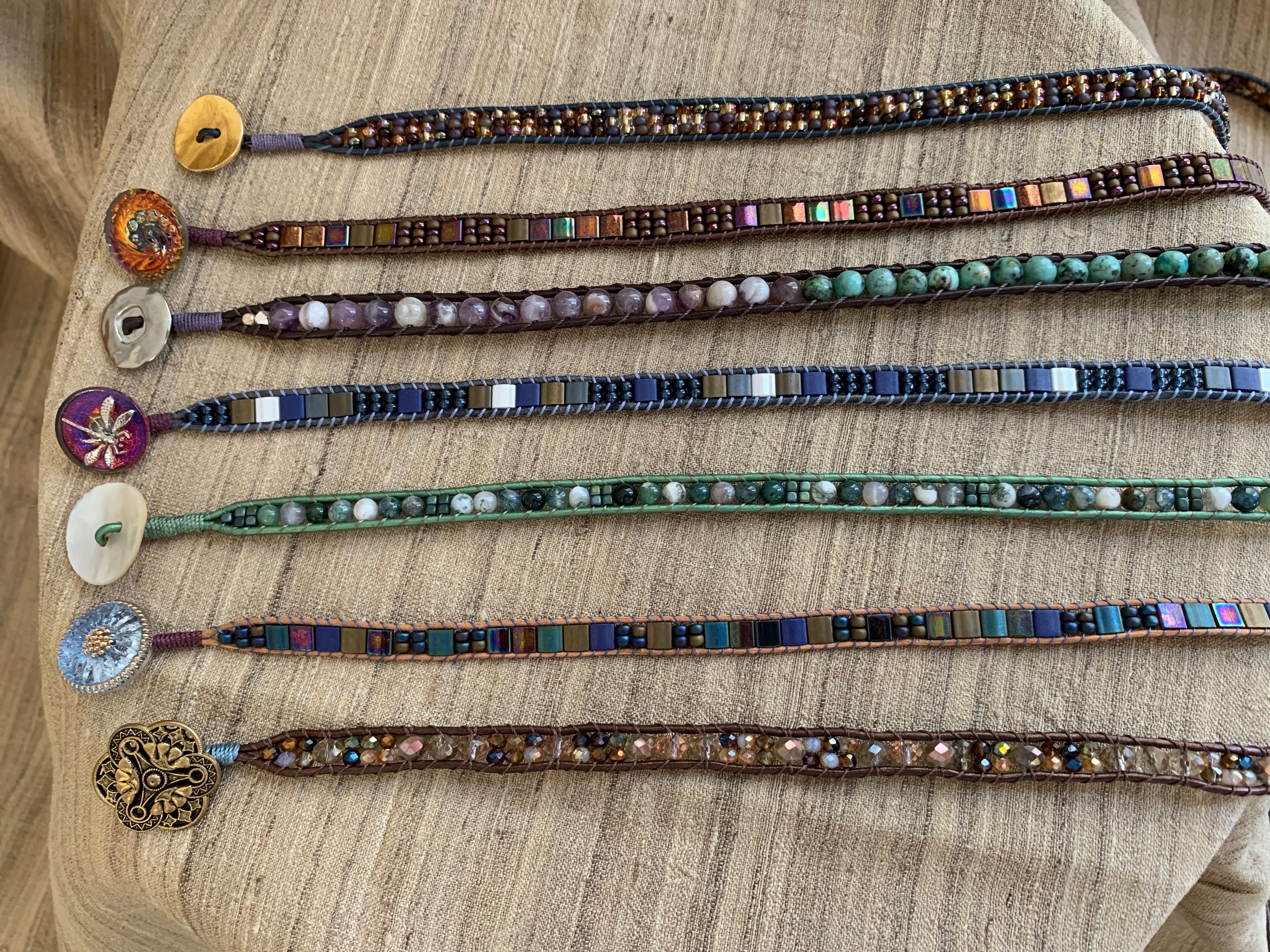 Several handmade beaded bracelets lined up side by side, each with different colors.